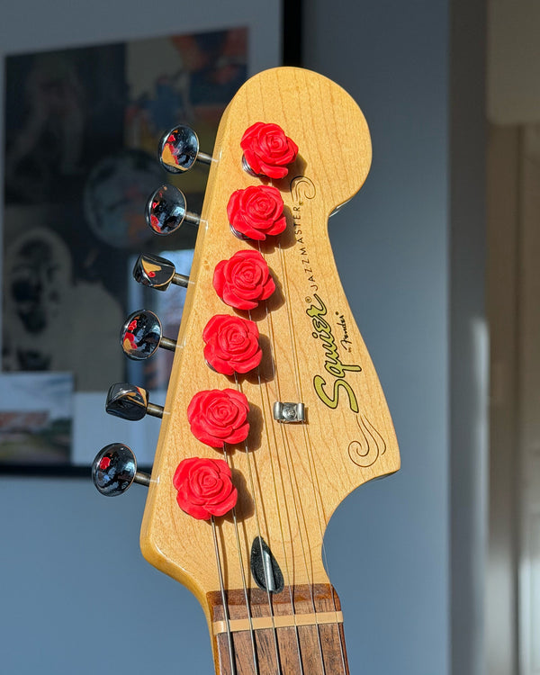 Guitar headstock with rose flower-shaped tuning pegs on a blurred background